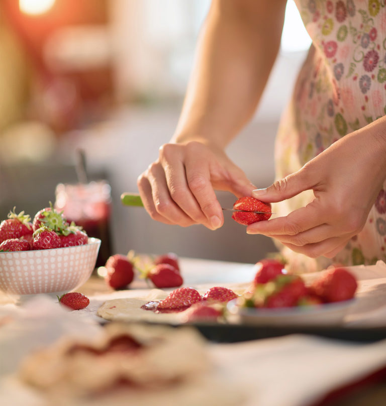 image des mains d'une femme préparant une tarte aux fraises