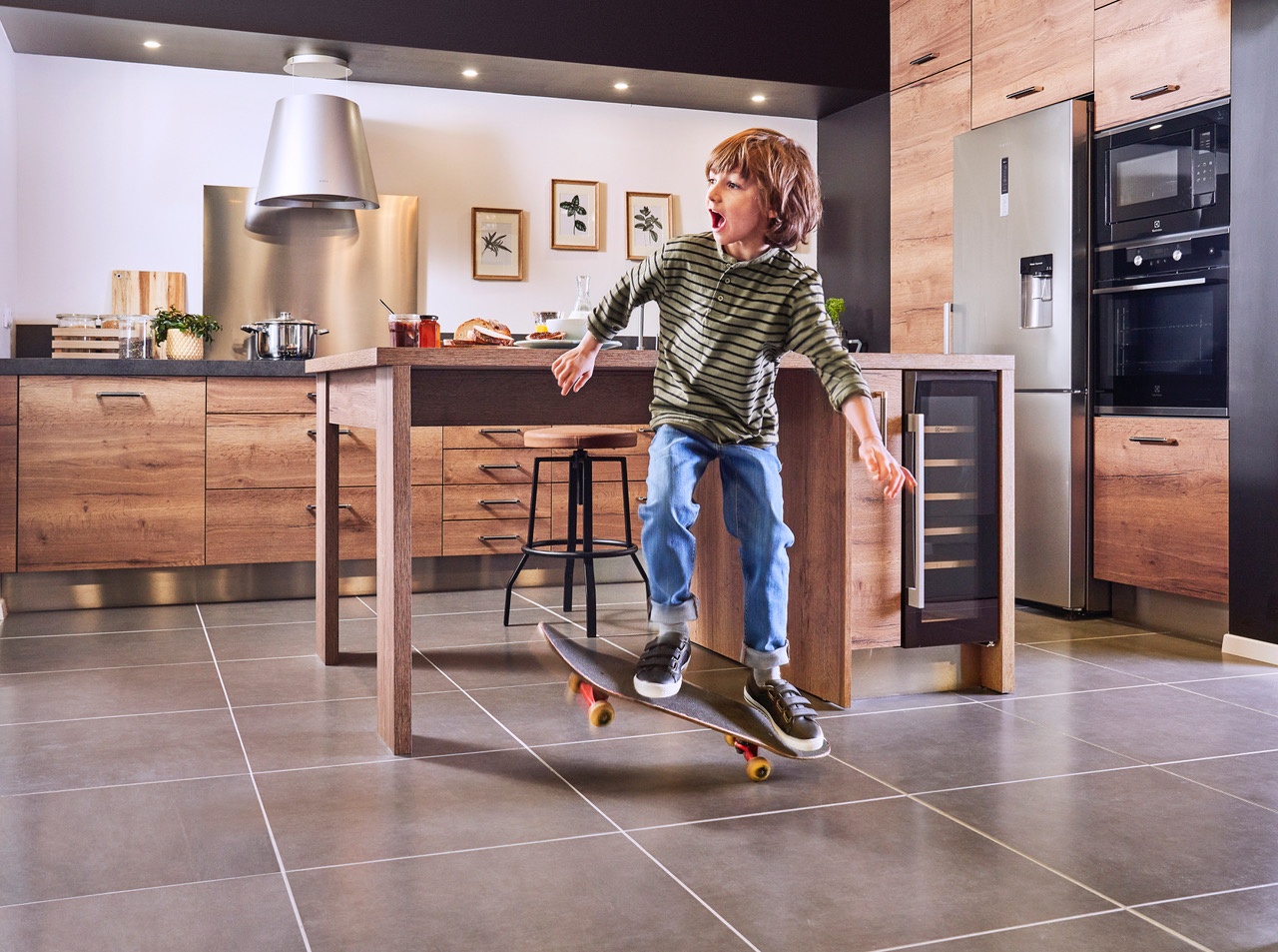 Photo lifestyle d'un garçon qui fait du skate dans une cuisine Comera