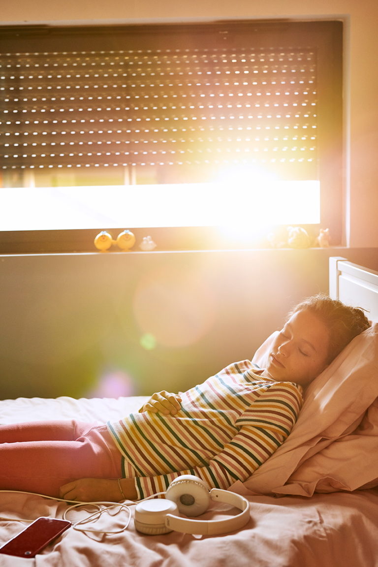 Photo d'une enfant dormant écoutantde la musique sur son lit avec un casque